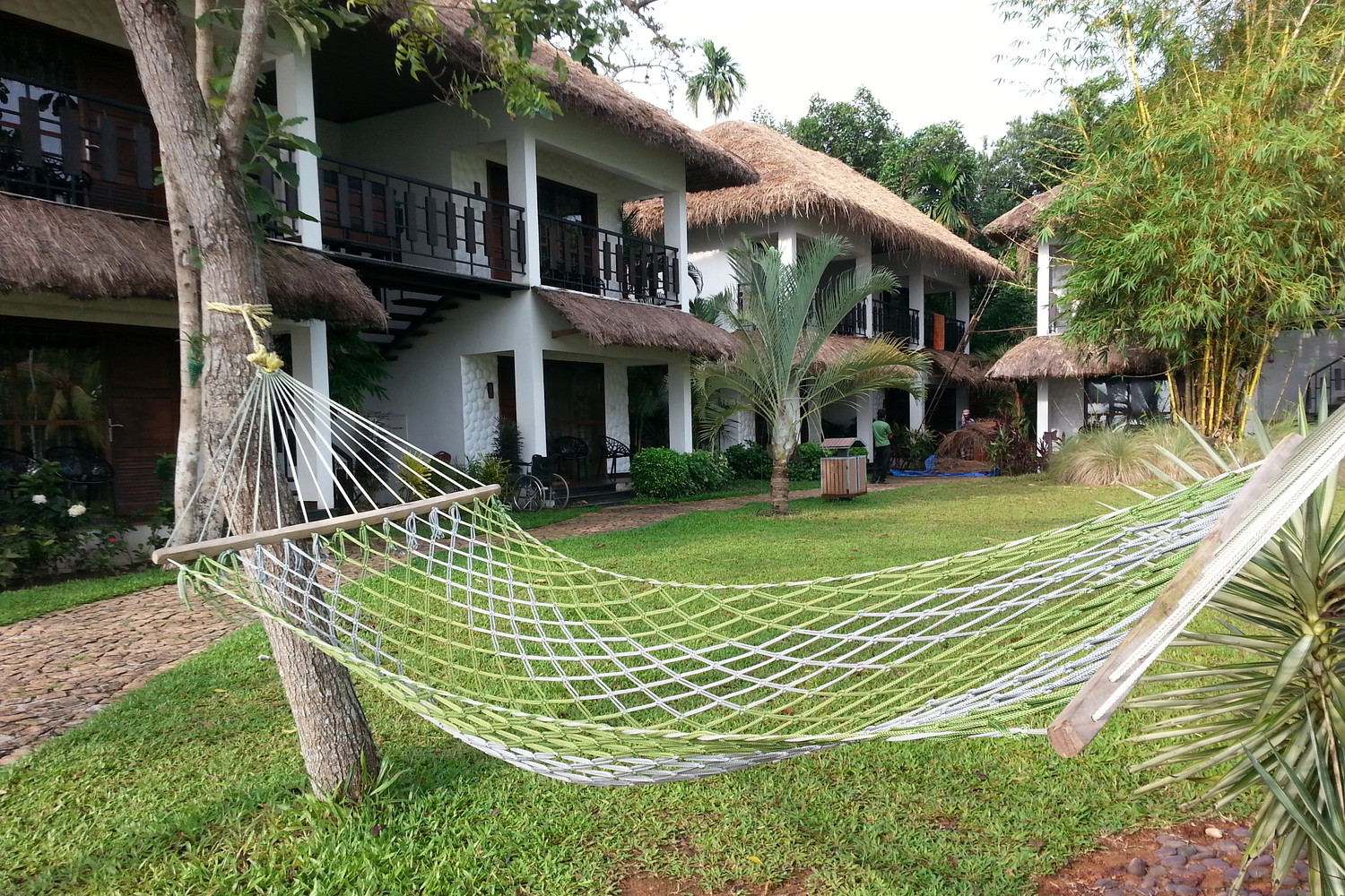 An empty hammock at a lawn with hotel rooms behind