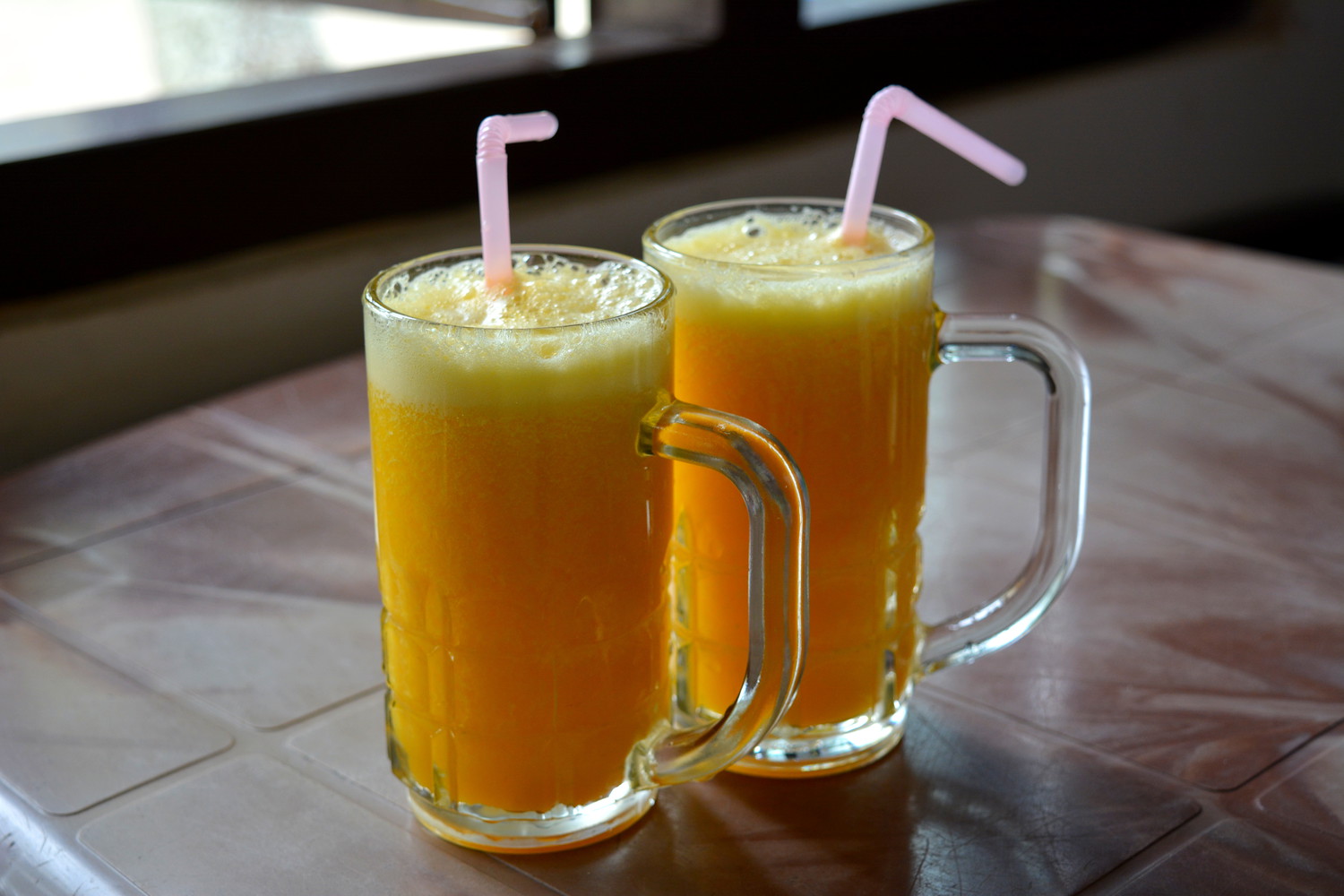 Two glasses of orange juice with pink straws