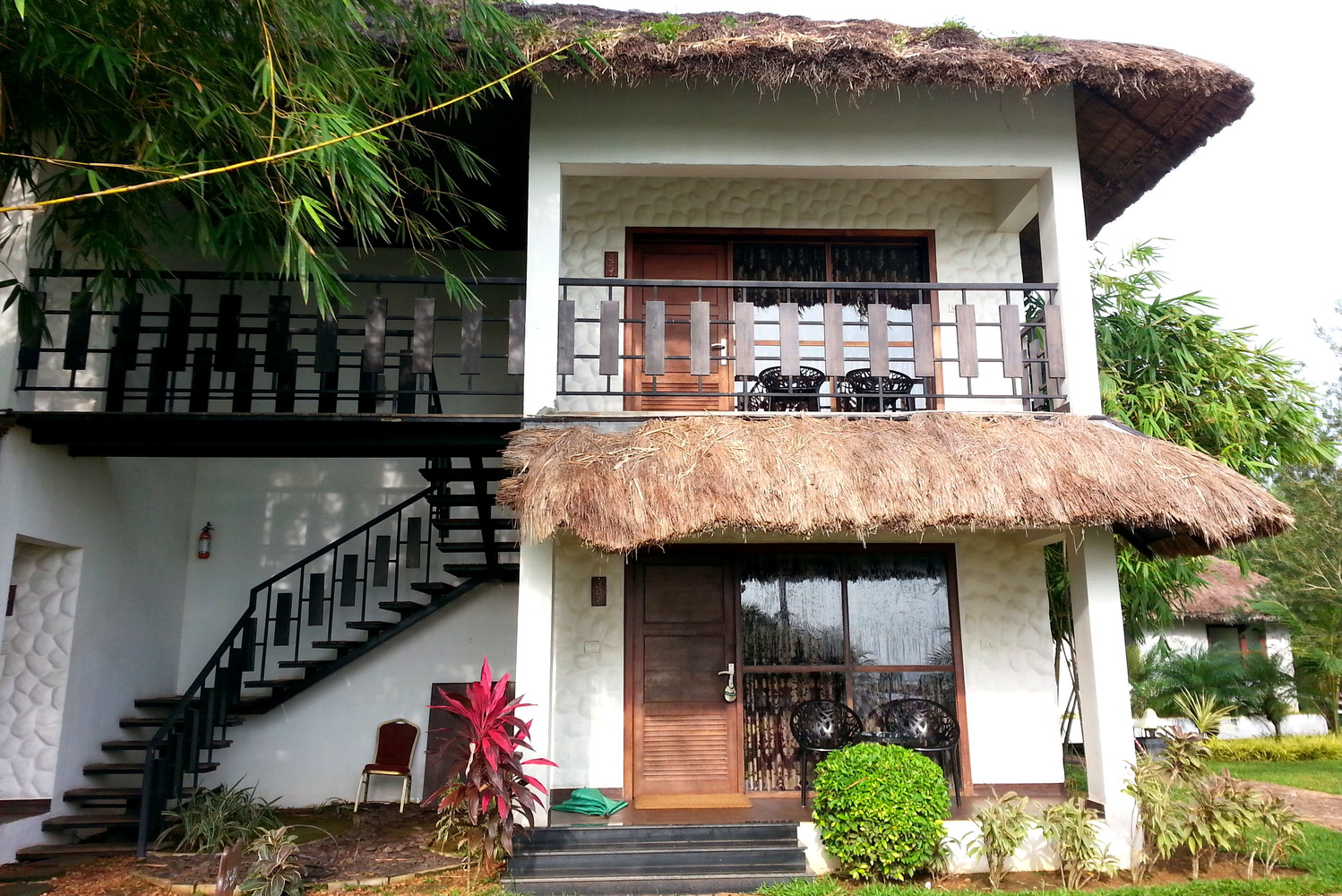 Two-storey building with stairs, wooden doors, and thatched awnings
