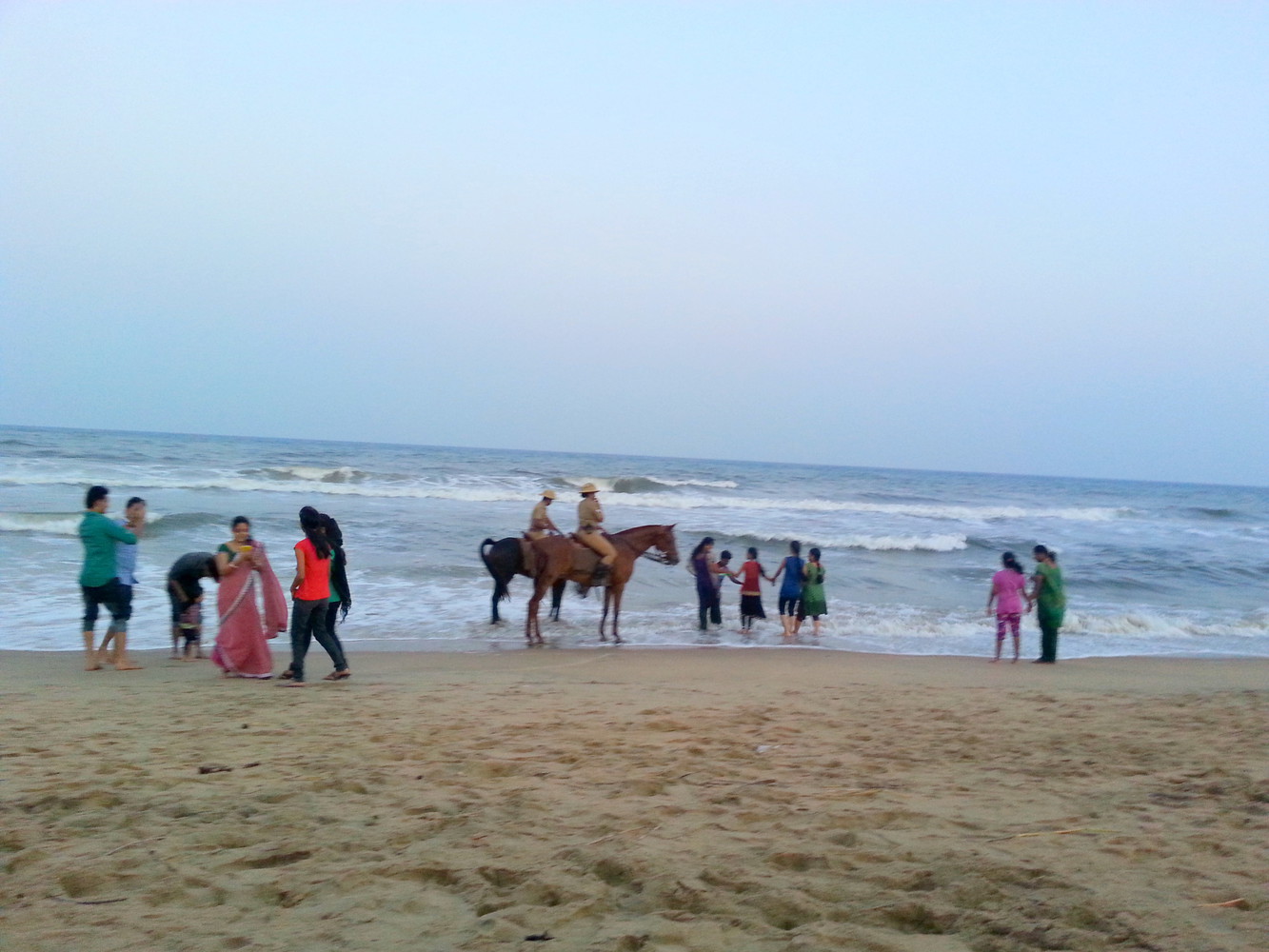 Visitors and cops on horses at a beach