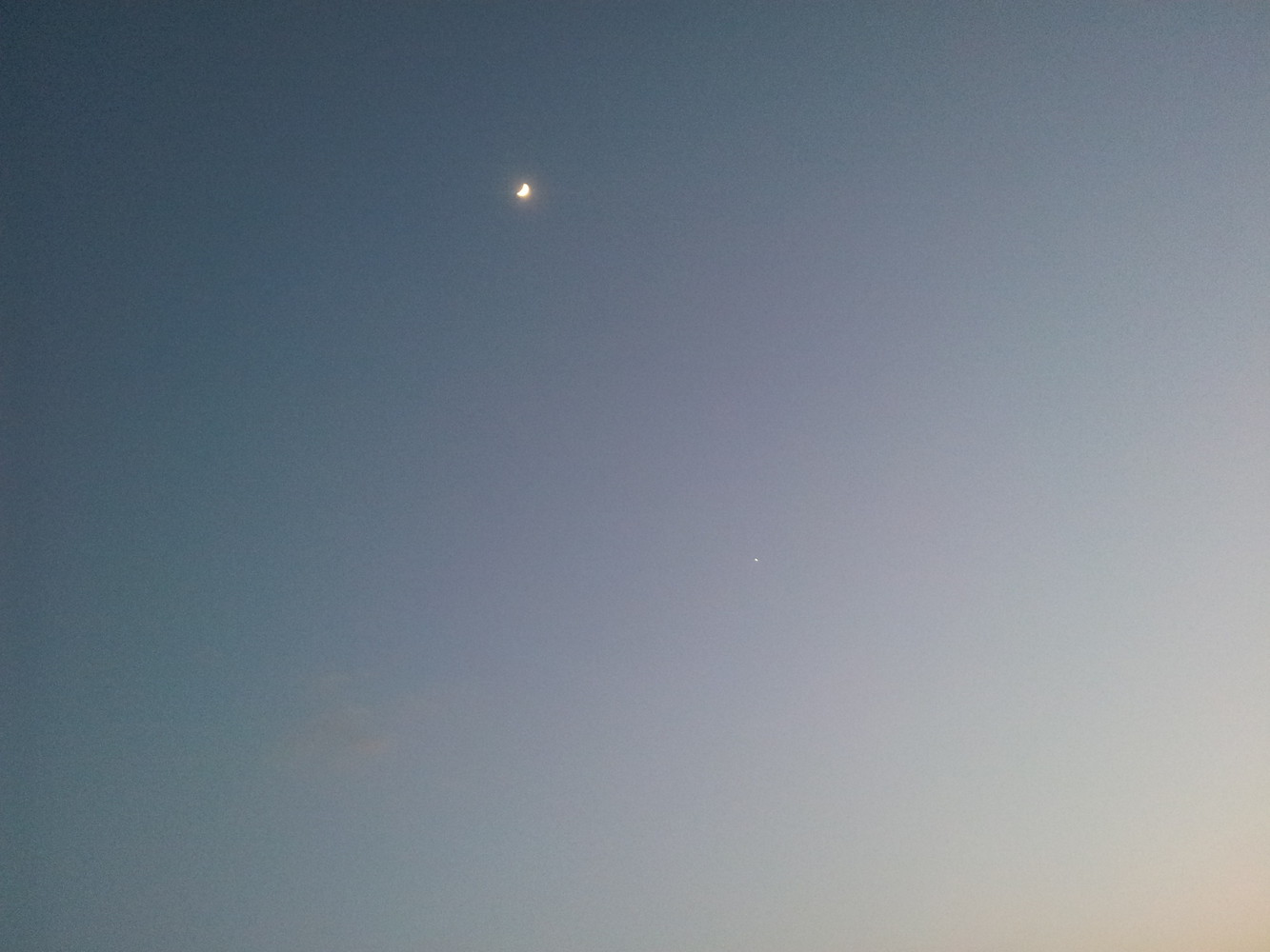 Crescent moon with Venus appearing as a tiny white dot to its bottom right
