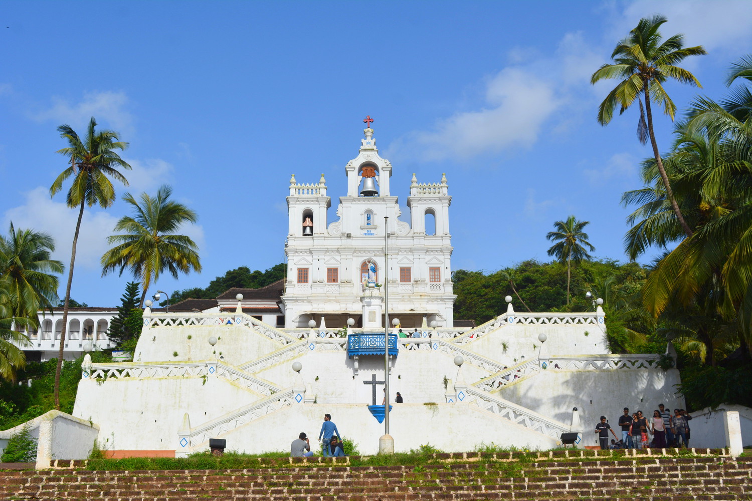 A colonial Portuguese Baroque style church atop a hill with zigzag stairs surrounded by palm trees