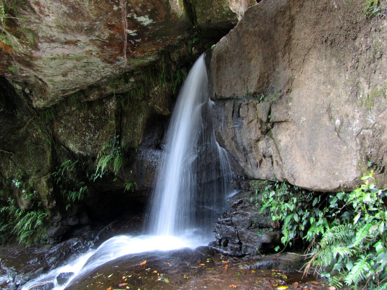 A waterfall with a stream of water escaping from a gap between rocks