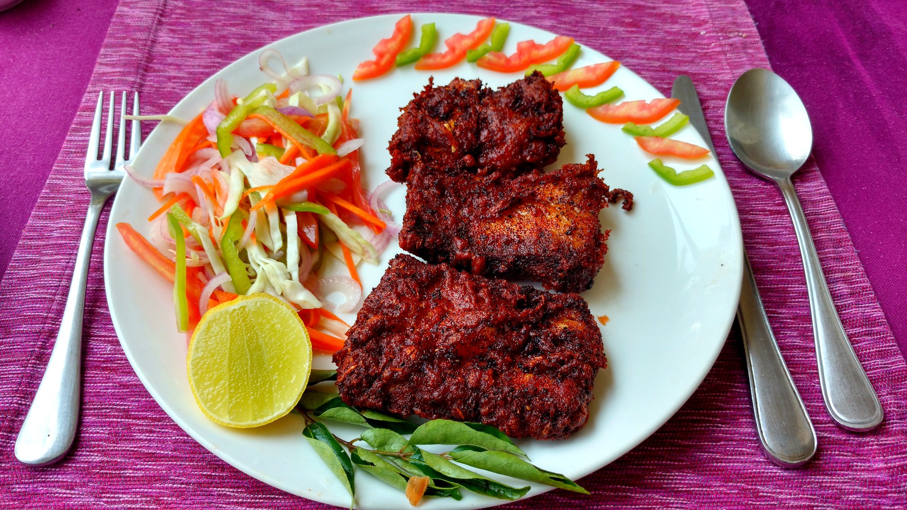 Three pieces of masala fried fish served with salad and a lemon slice