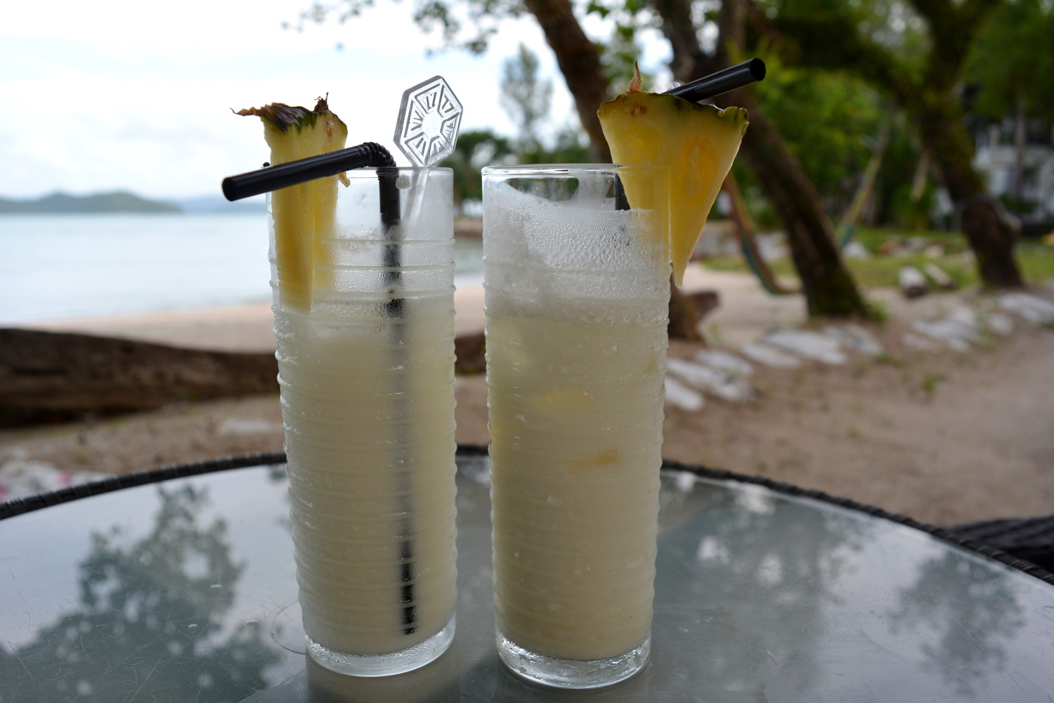 Two glasses of Islander's rum punch served with slices of pineapple at an open air beachside restaurant