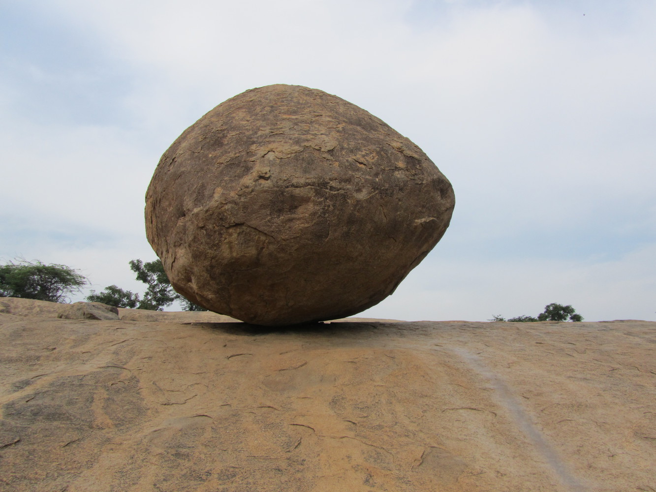 A gigantic granite boulder known as Krishna's Butterball resting on a short incline