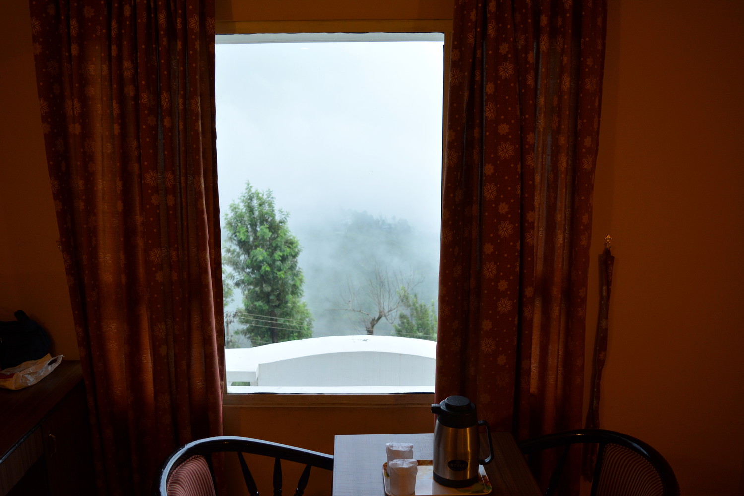Hills covered with mist visible from the window of a hotel room