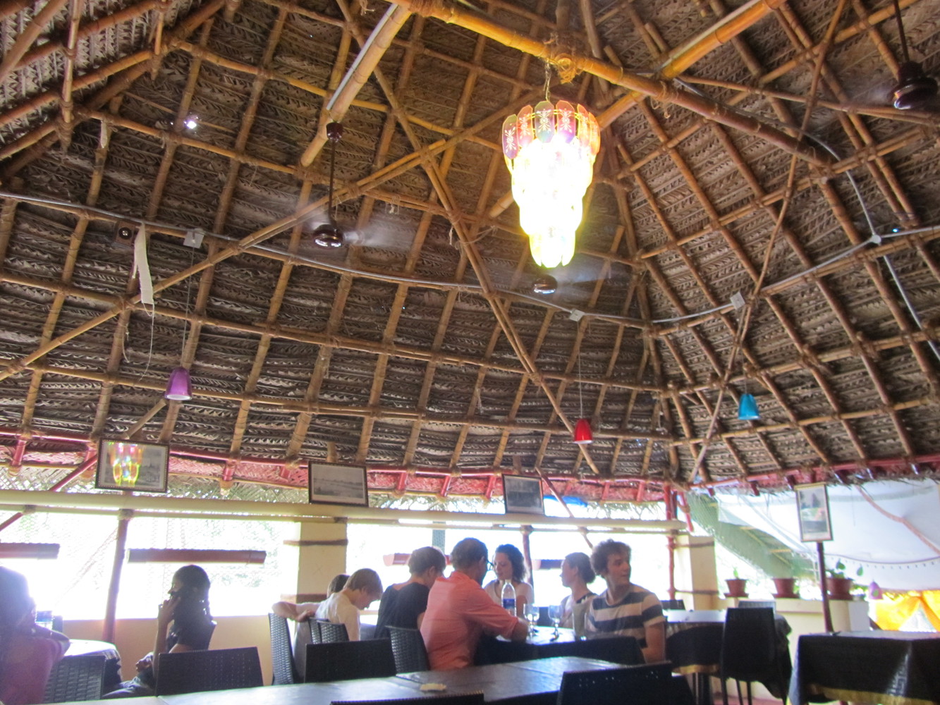 A rooftop restaurant with thatched ceiling, tables, and diners