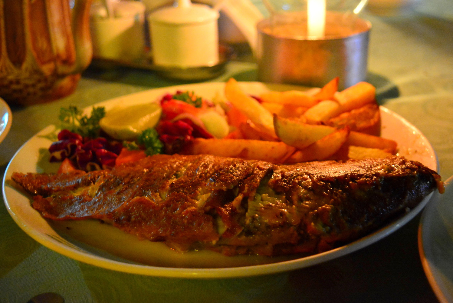 Masala fried red snapper served with fries, salad, and a lemon slice
