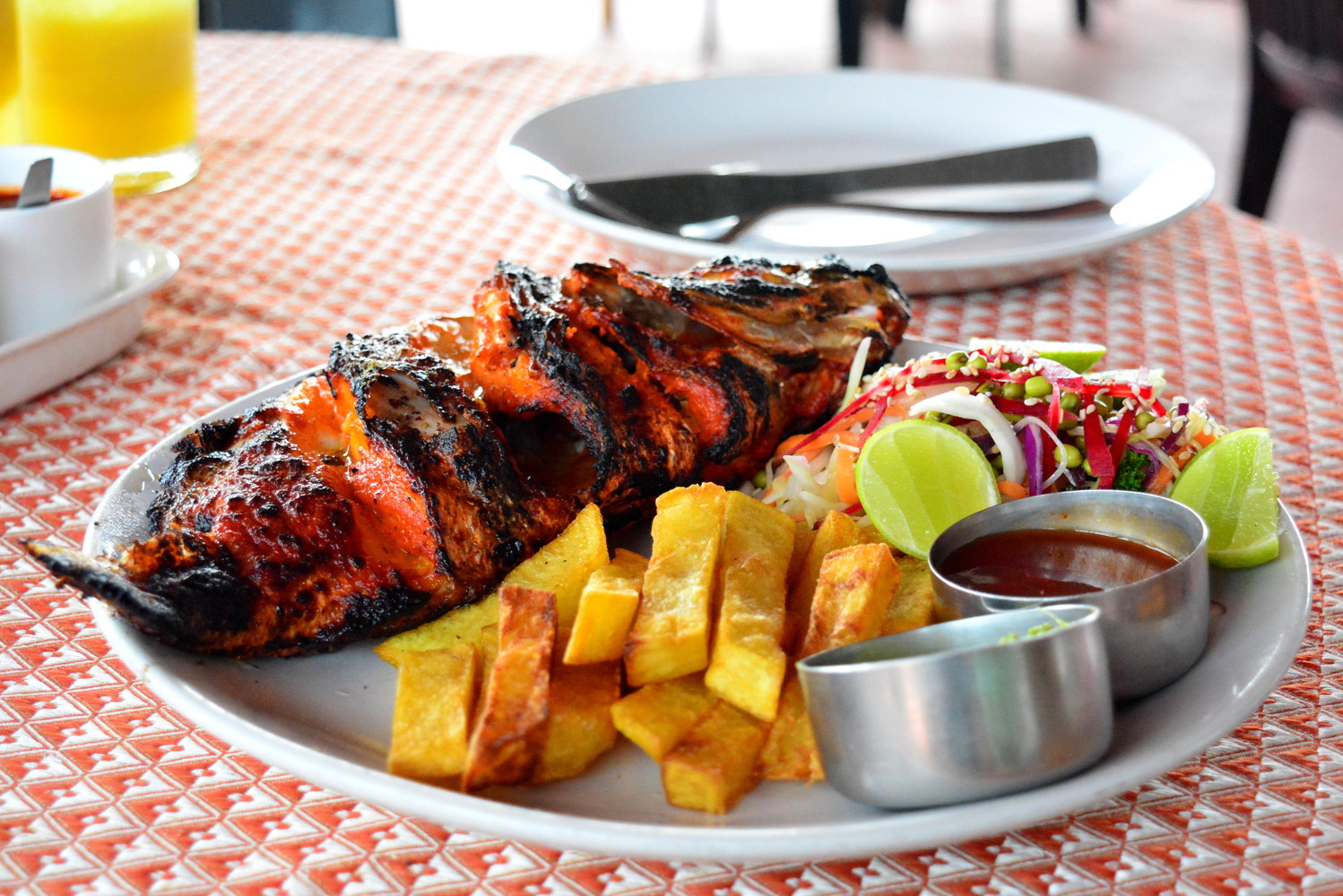 Tandoor red snapper served with fries, salad, and lemon slices